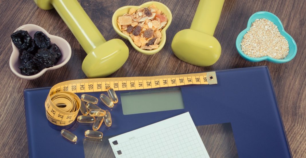 Digital scale with tape measure, tablets, dumbbells and healthy nutrition, slimming concept