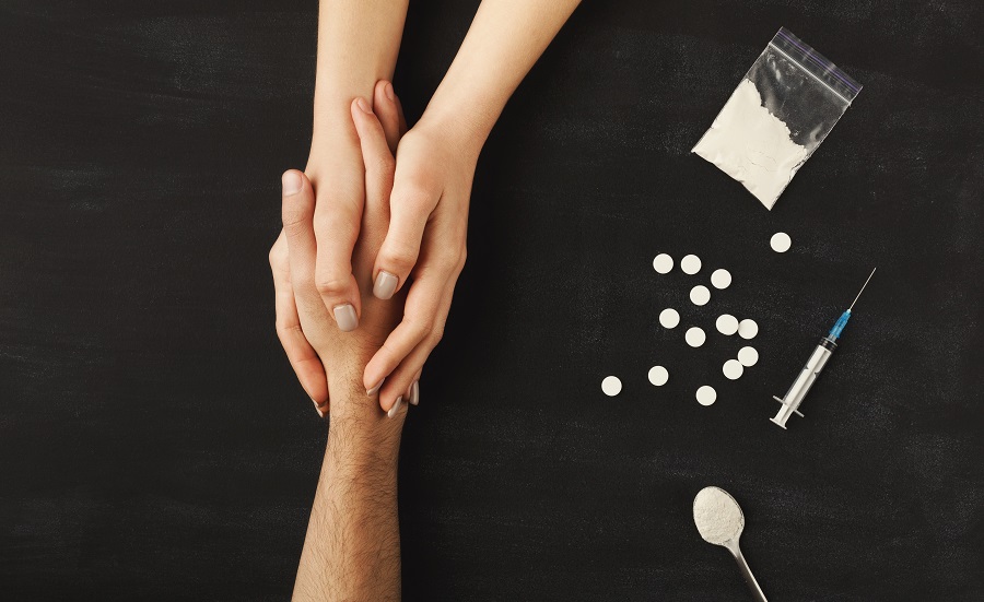 opiate withdrawl symptoms and treatment Drug addict hands asking for help on dark table with cooked heroine, pills, spoon and plastic bag. Concept for drug addiction and International Day against Drug Abuse, top view